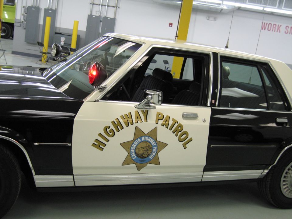 Close-up of a CHP sedan door reading HIGHWAY PATROL with the gold star emblem