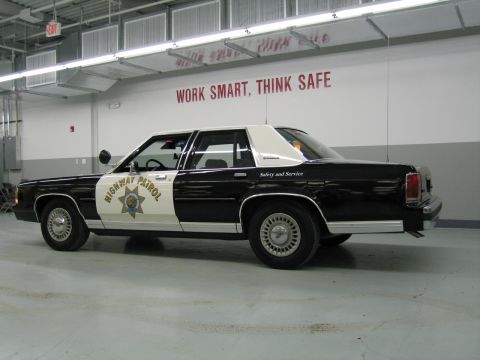 1991 Ford LTD Crown Victoria - Rear three-quarter side view of a black-and-white California Highway Patrol Ford sedan with Safety and Service lettering.