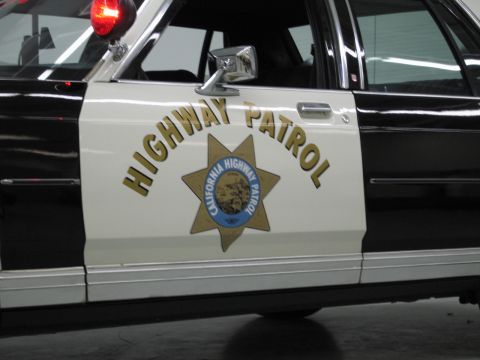 1991 Ford LTD Crown Victoria - Close-up of a police car front door showing Highway Patrol lettering and the California Highway Patrol gold star emblem.