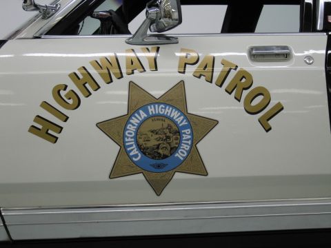 1991 Ford LTD Crown Victoria - Close-up of a white police rear door showing gold Highway Patrol lettering and the California Highway Patrol star emblem.