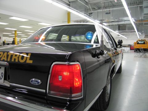 1991 Ford LTD Crown Victoria - Rear three-quarter close-up of a black CHP Ford sedan showing the taillight, Ford emblem, and Patrol lettering.