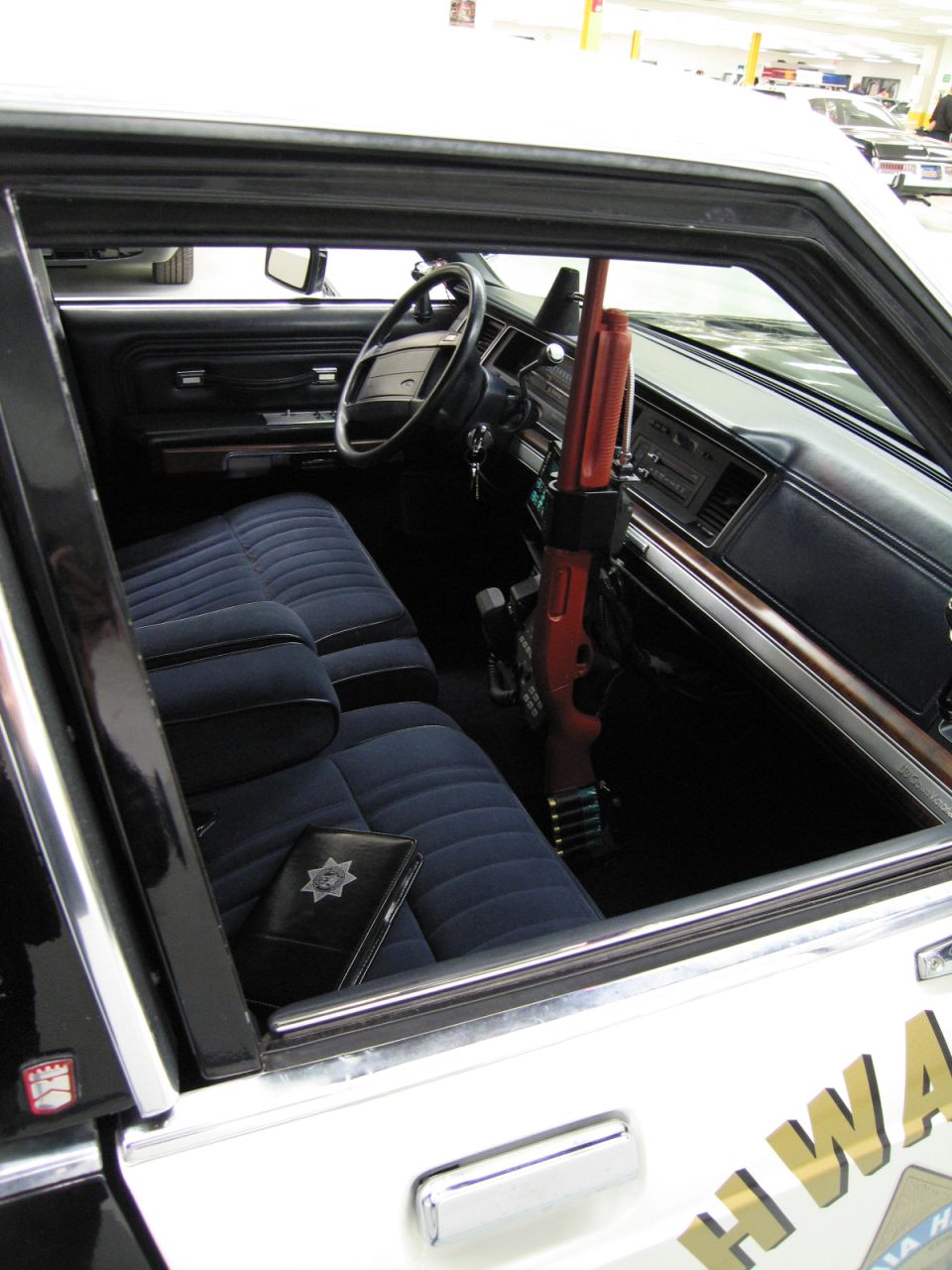 Interior of CHP police car showing bench seat, dash, and shotgun mount