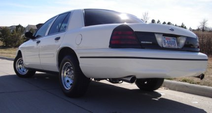 2000 Ford Crown Victoria - Rear quarter view of a white 2000 Ford Crown Victoria, aftermarket chrome wheels and a black accent panel on the rear panel.