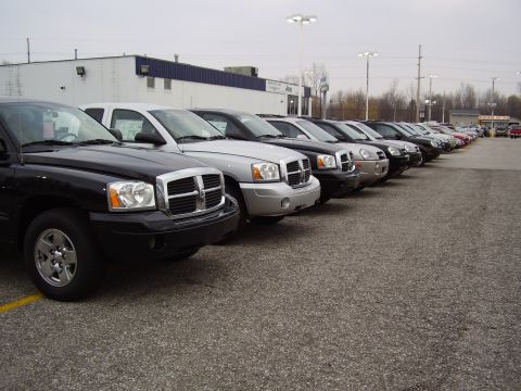 1997 Ford Taurus - Multiple pickup trucks are parked in a lot outside a building.