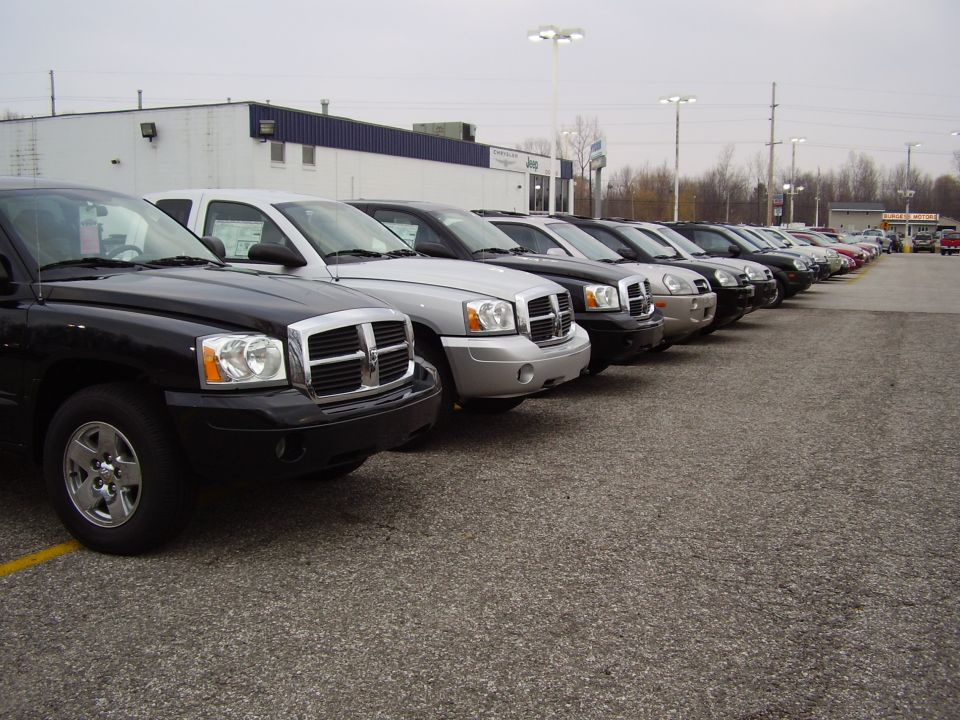 Black pickup truck front corner, silver pickup truck next to it, parked in lot