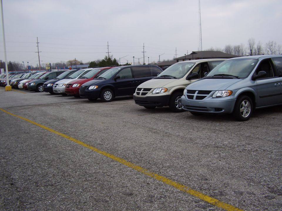 Row of minivans parked in a lot, front view