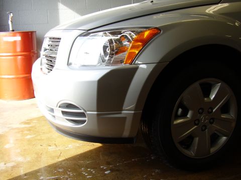 1997 Ford Taurus - The front end of a silver Dodge Caliber is visible, parked indoors with sunlight casting shadows.
