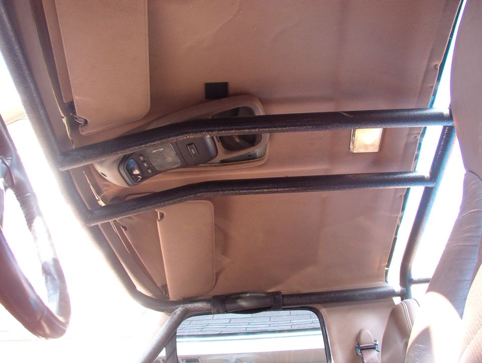 Tan headliner and overhead console with black roll cage bars inside a Ford Bronco