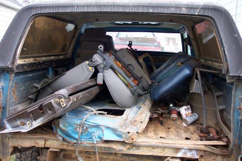 1978 Ford Bronco - The interior of a vehicle is cluttered with disassembled seats and various parts, suggesting a restoration or repair project.