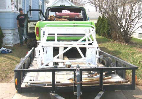1978 Ford Bronco - A man stands by a green pickup truck while a roll cage is loaded onto a trailer.