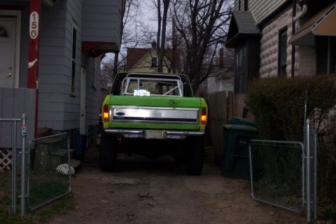 1978 Ford Bronco - Rear view of a lifted green 1978 Ford Bronco with a roll cage, parked in a driveway.