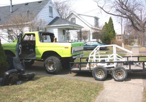 1978 Ford Bronco - A lime green 1978 Ford Bronco is parked in a driveway, towing a trailer with a white roll cage.