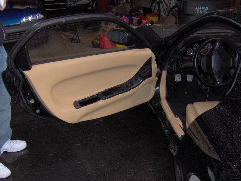 1993 Mazda RX-7 - Interior view of a car with the driver's door open, revealing the dashboard and tan upholstery.