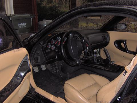 1993 Mazda RX-7 - Interior view of a black car with tan leather seats and dashboard, showing the steering wheel and gauges.