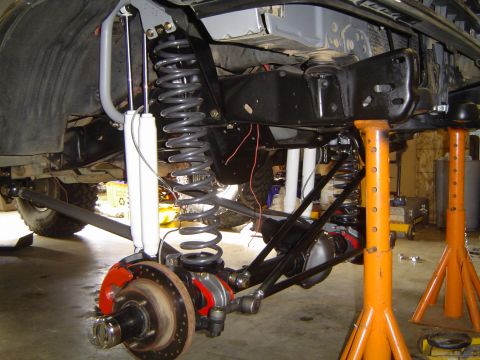 1989 Ford Bronco - Detailed view of the front suspension system, including coil springs, shocks, and brake components, during a repair or upgrade.