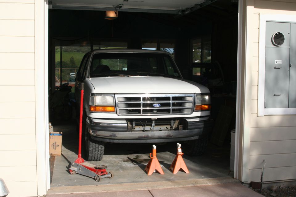 White Ford F-series truck on jack stands in an open residential garage
