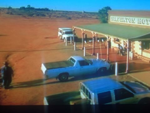1971 Ford Ranchero - A dusty scene outside the Silverton Hotel shows several vehicles parked in the arid landscape.