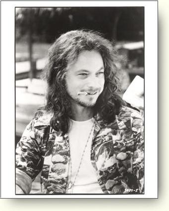 1991 Ford Bronco - A man with long, wavy hair and a cigarette dangling from his lips is captured in a candid outdoor shot.