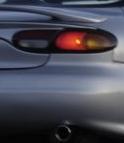 1999 Ford Taurus - Close-up of a silver car's rear taillight and exhaust pipe.