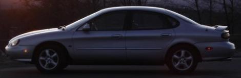 1999 Ford Taurus - Side profile of a silver 1999 Ford Taurus sedan with a spoiler.