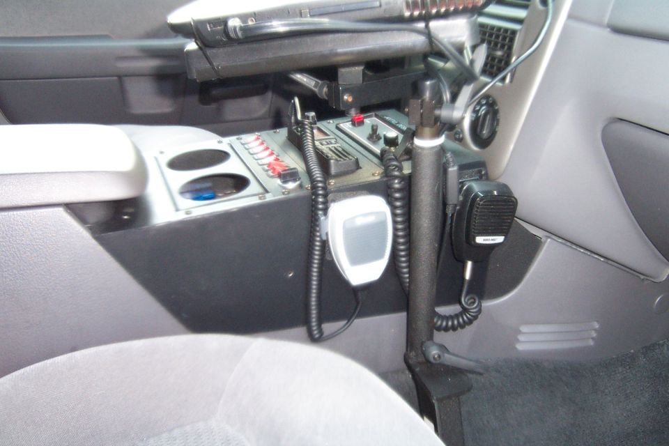 Police car interior console with two microphones, cup holders, and multiple switches