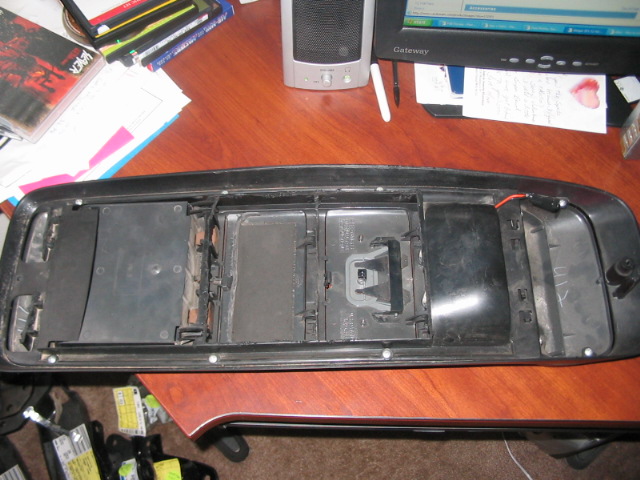 Interior center console removed from a vehicle, showing the empty housing and mounting points