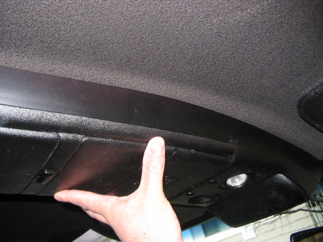 Hand pressing on the overhead console storage compartment of a vehicle