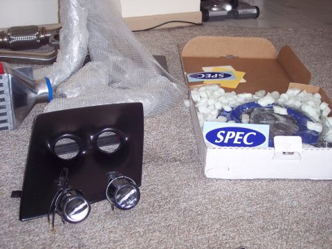 1995 Ford Probe - Automotive parts are laid out on a carpeted surface, including a black component and a box with packing peanuts.