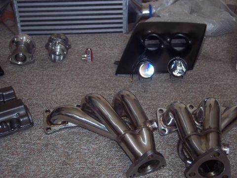 1995 Ford Probe - Collection of automotive performance parts including exhaust manifolds and a blow-off valve.