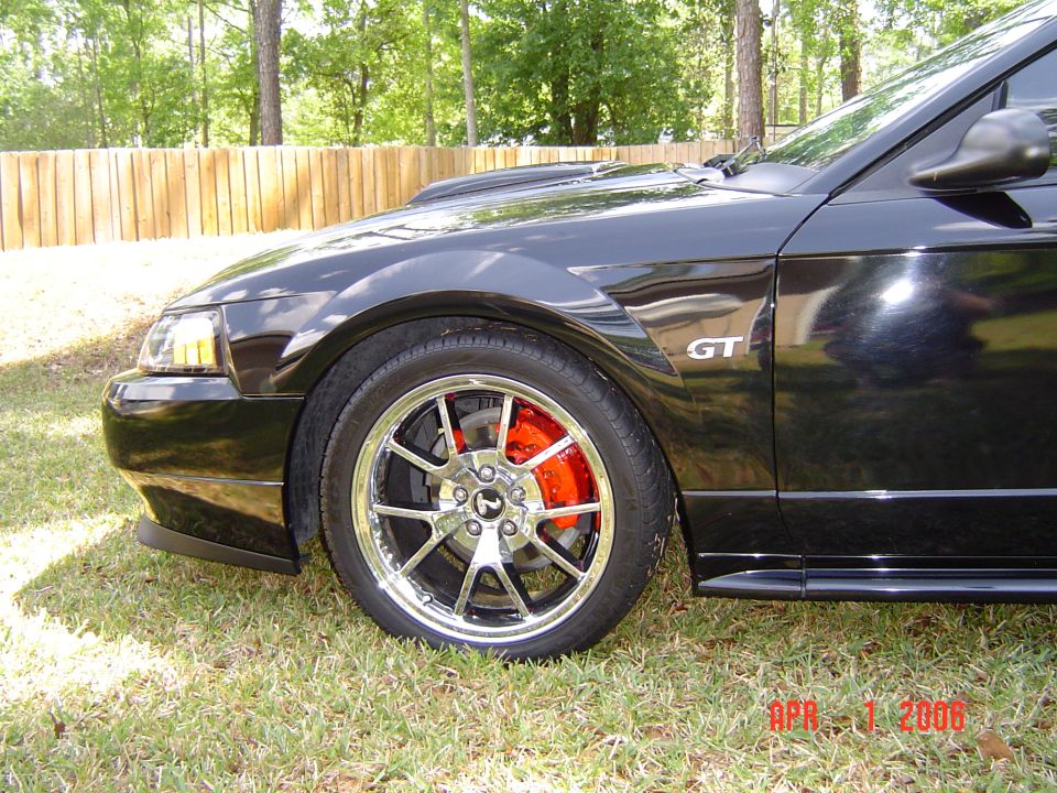 Front corner of a black Ford Mustang GT on chrome wheels with red brakes