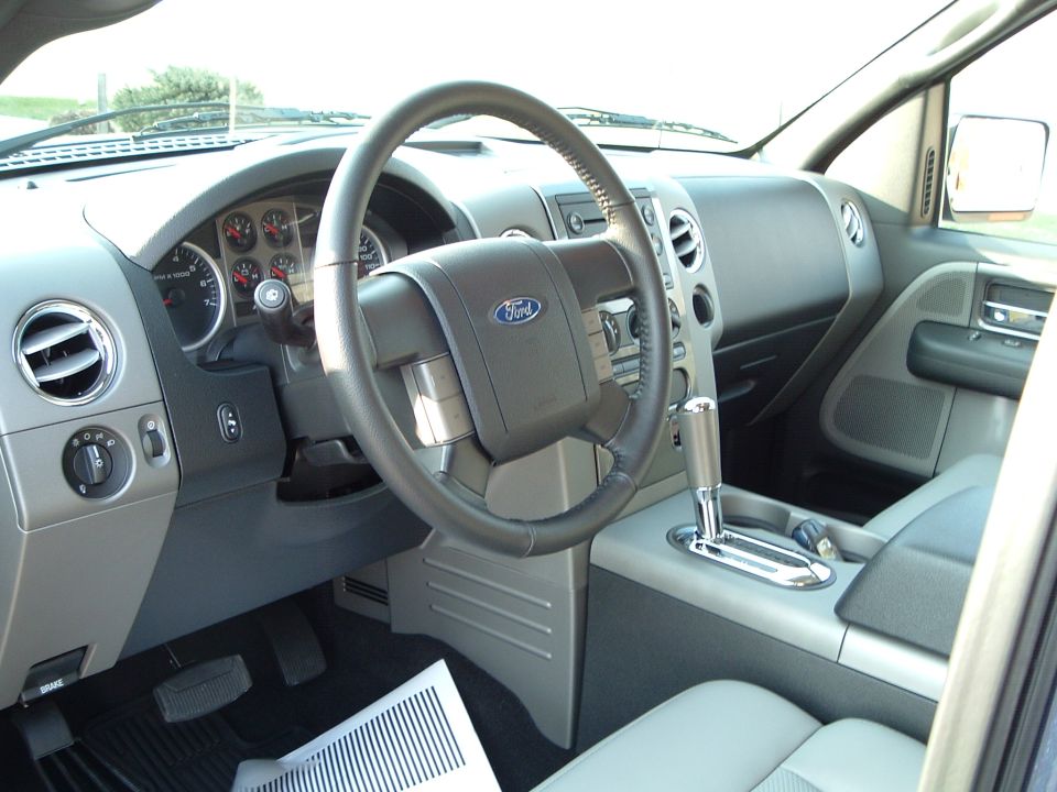 Gray Ford truck interior with leather steering wheel and floor shifter
