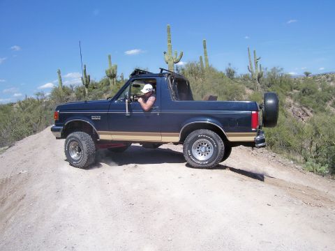 1991 Ford Bronco - This 1991 Ford Bronco is navigating a dusty desert trail under a clear blue sky.