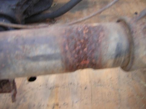 1979 Ford Bronco - Close-up of a heavily rusted metal pipe, likely part of a vehicle's undercarriage.