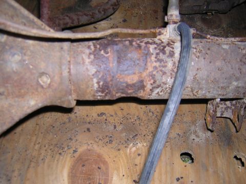 1979 Ford Bronco - Close-up of rusted metal pipe and wooden surface, likely part of a vehicle's undercarriage.