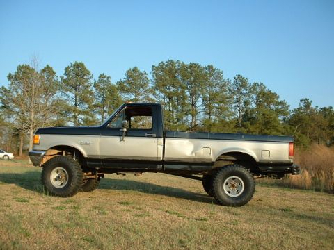 1987 Ford F-150 - This pickup truck has a two-tone paint job and appears to be lifted with large tires.