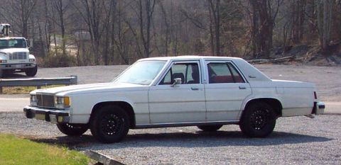 1985 Ford Crown Victoria LTD - White 1985 Ford Crown Victoria LTD parked on gravel with a white truck in the background.