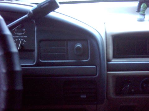 1996 Ford Bronco - Dim interior shot of a 1990s Ford truck dashboard from the passenger side, showing the fuel gauge marked "UNLEADED FUEL ONLY", the dash ven…