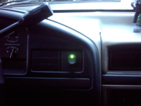 1996 Ford Bronco - Ford truck dashboard shot in low light with a green-illuminated auxiliary toggle switch glowing in the dash bezel beside the vent, indicati…