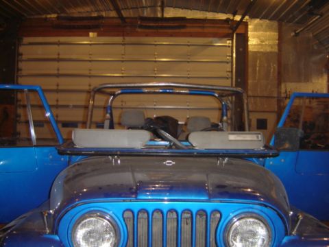 1992 Ford Bronco - Blue Jeep CJ front end and interior visible inside a garage with doors open.