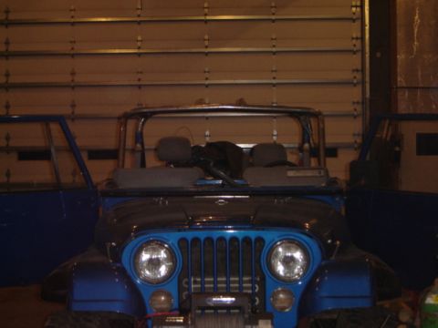 1992 Ford Bronco - A blue Jeep Wrangler is parked in front of a garage door with its doors open, revealing the interior and a winch.