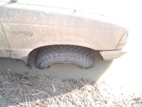 1981 Ford Bronco - A Ford Ranger is stuck in the mud, with its front wheel deep in the mire.