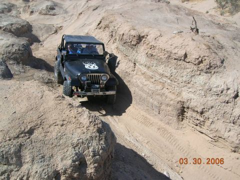1985 Ford Bronco - Jeep CJ-7 tackling a challenging off-road course in a desert canyon.