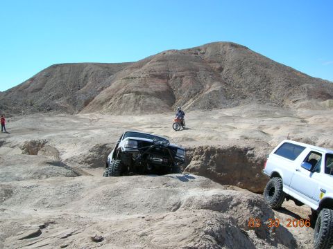 1985 Ford Bronco - Two Ford Broncos tackle a challenging off-road course in a desert environment.