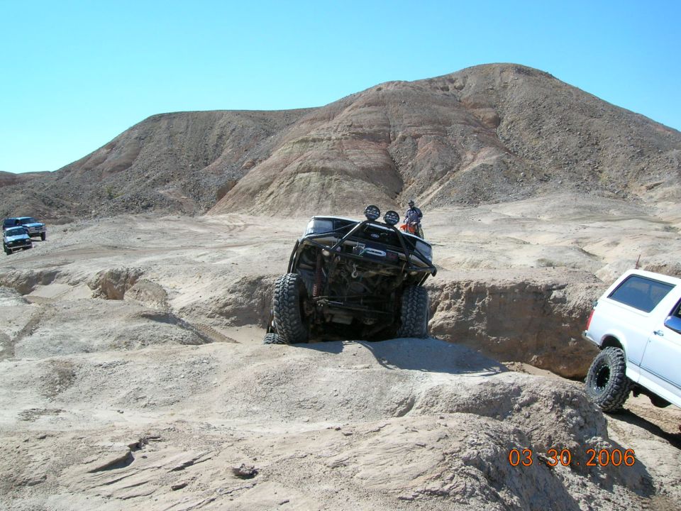 Off-road vehicles on a rocky desert trail with a person standing on one