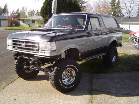 1989 Ford Bronco - A lifted 1987 Ford Bronco with a two-tone paint scheme is parked on a paved surface.
