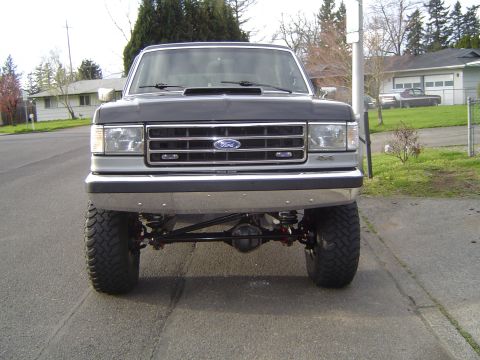 1989 Ford Bronco - This lifted Ford truck features a prominent grille and a modified suspension system.