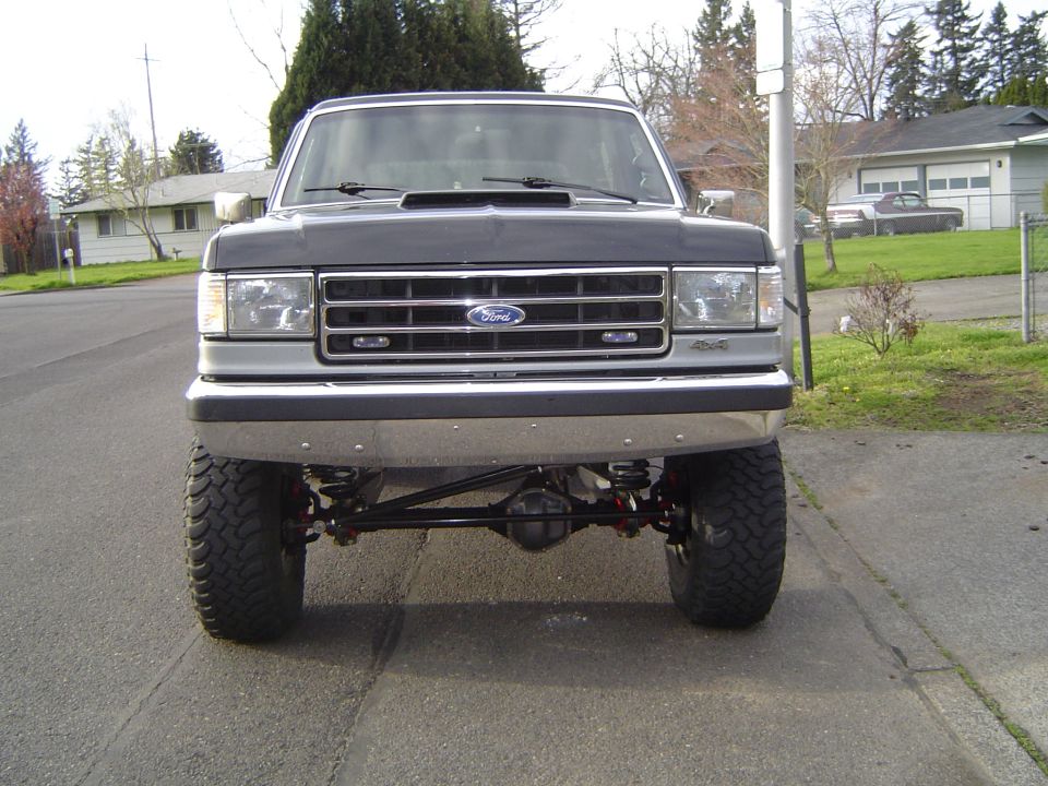 Lifted gray Ford Bronco front view showing exposed solid front axle and big tires