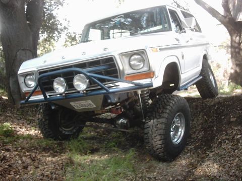 1978 Ford Bronco - This 1978 Ford Bronco features a custom front bumper and large off-road tires, captured while navigating challenging terrain.