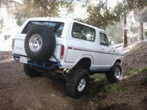 1978 Ford Bronco - This white 1978 Ford Bronco is shown from the rear, a spare tire mounted on the back and lifted suspension for off-road use.