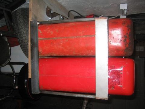 1986 Ford Bronco - A metal rack holds two red jerry cans, with a spare tire visible in the background.